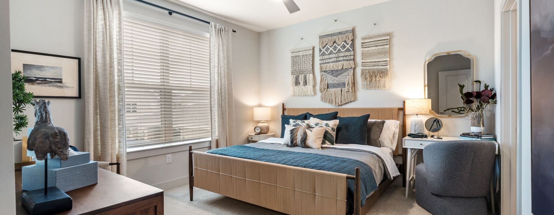a bedroom with a bed window plants mirror and lamps
